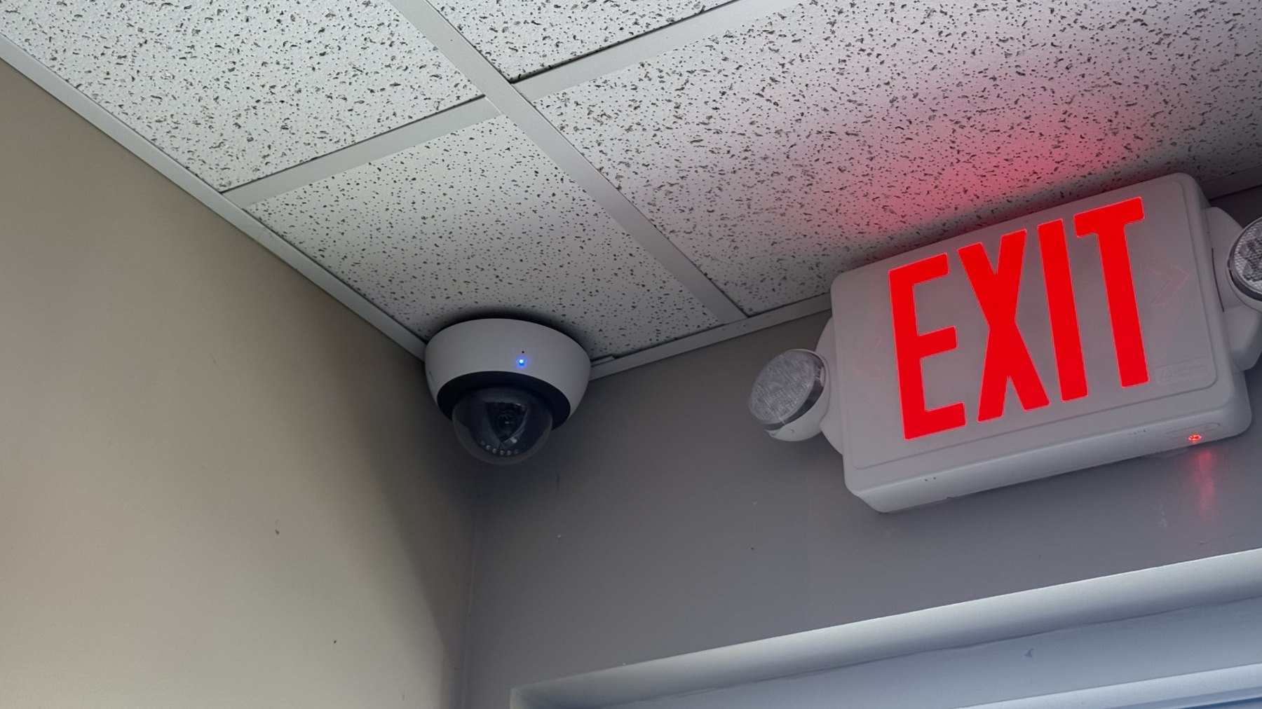 Ceiling mounted surveillance camera near exit sign