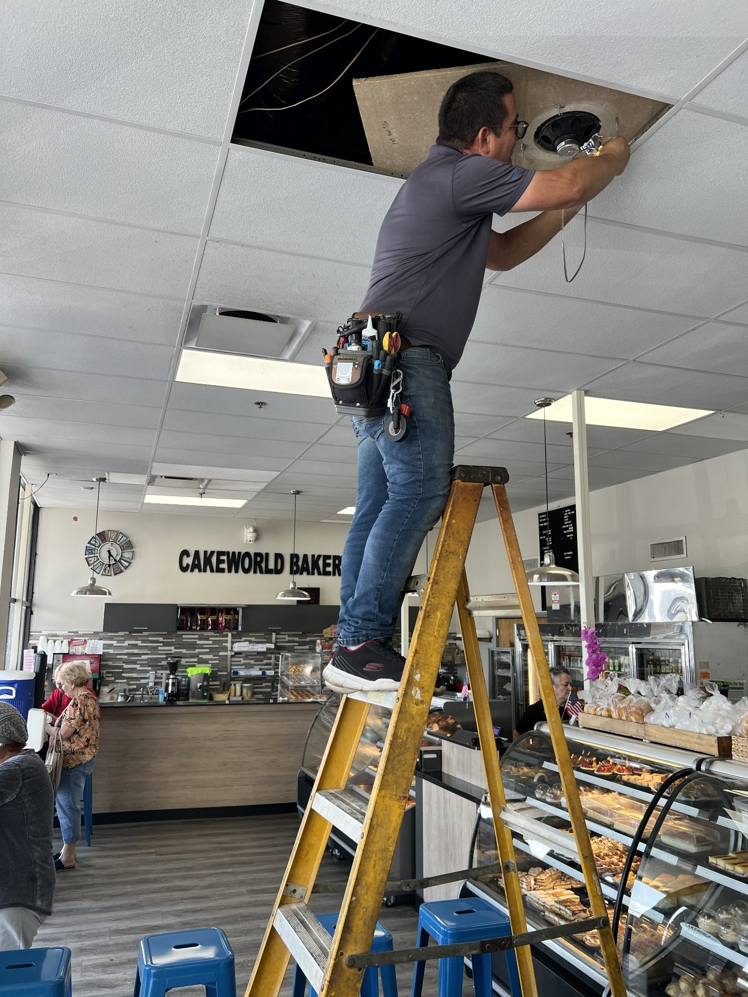 Technician working above ceiling tiles in bakery